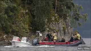 Rescue boats patrol near the shore of the small, wooded island of Utoeya