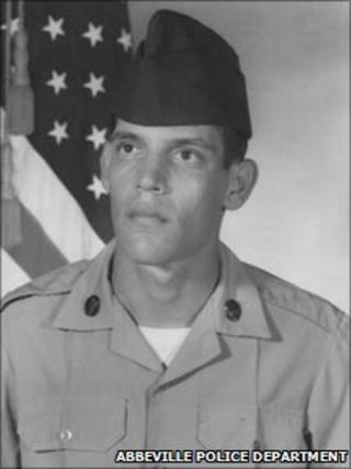 A photograph of Joseph W Schexnider sitting next to an American flag