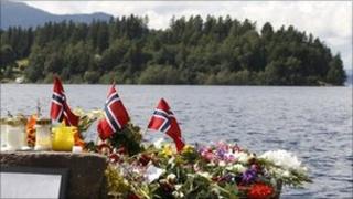 Norwegian flags and flowers on the lakeshore in front of Utoeya island to commemorate victims of the shootings there - 27 July 2011