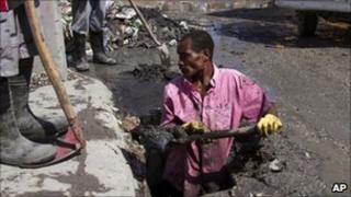 A worker from a private company cleans a drainage in preparation for Tropical Storm Emily in Port-au-Prince, Haiti, Wednesday, 3 August 2011