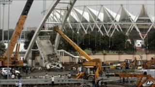 A crane lifts debris from a pedestrian bridge that collapsed outside the Jawaharlal Nehru Stadium (22 September 2010)