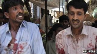 Two rescuers remove a casualty from the blast site in Dara Allah Yar, 14 August