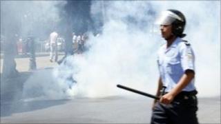 police officer with truncheon, teargas and people in background