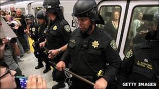 Bart police keep back protesters from a departing train in San Francisco