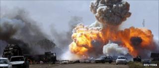 Vehicles belonging to forces loyal to Libyan leader Muammar Gaddafi explode after an air strike by coalition forces, along a road between Benghazi and Ajdabiya in this March 20, 2011 file photo