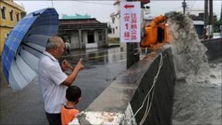A man shows his grandson a water pump (R) extracting overflowing water caused by rain brought by Typhoon Nanmadol in Linbian in Taiwan"s southern Pingtung county on August 29, 2011.