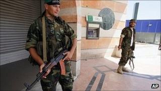 Libyan rebels stand guard outside a bank in Tripoli