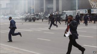 Opposition politician Honore Okundji, left, runs as police chase protesters during a demonstration in Kinshasa, DR Congo, 1 September 2011