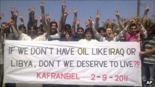 Mobile phone photo published by the Shaam News Network of anti-Assad protesters holding a banner during a demonstration against the Syrian regime, at Kfar Nebel, in Idlib province, Syria, on 2 September 2011