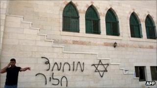 Man speaks on phone outside graffiti-daubed mosque in Kasra, 5 September 2011