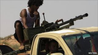 Anti-Gaddafi fighters drive their pickup with a heavy machine gun, around 65km (40 miles) east of Sirte