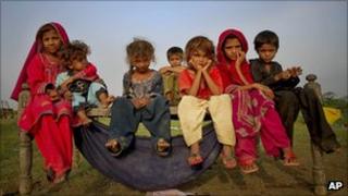 Children, displaced by floods, sit outside their makeshift tent at a roadside in Pakistan's Sindh province