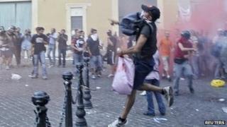 Anti-austerity protesters throw flares during a protest in front of the Italian Parliament building in downtown Rome