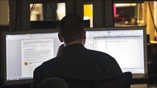 Generic image of man reading from computer screens