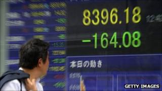 Consumer walking in front of a stock board in Tokyo