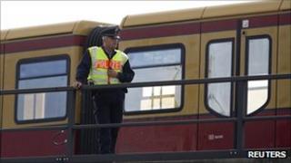 A police officer keeps watch on a rail track in front of a halted S-Bahn commuter train after an incendiary device was found on the tracks in Berlin