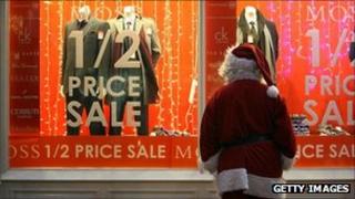 Someone dressed as Father Christmas looking at a pre-Christmas window display