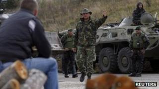 A NATO Kosovo Force (KFOR) soldier gestures towards a Kosovo Serb man in the village of Zupce