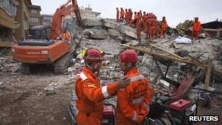 Two members of a Turkish search and rescue team talk to each other as others search a collapsed building for earthquake survivors in Ercis