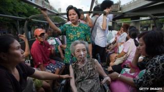 Bangkok residents sit in a truck as they drive away from a flooded area of the capital on 26 October 2011