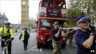 A team of 10 police officers and 10 members of the Armed Forces pull a fully laden double-decker bus for one mile