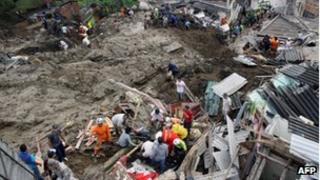 Rescue workers search the mid for survivors of a landslide