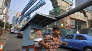 An Indonesian vendor pulls his food cart on the road next to an elevated road construction in central Jakarta.