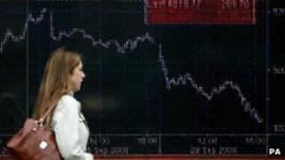 Woman walks past share index screen