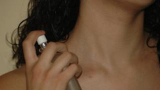 Young woman spraying perfume onto her neck