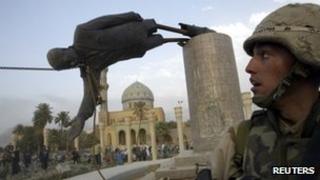 US Marine Kirk Dalrymple watches as a statue of Iraq's President Saddam Hussein falls 9 April 2003