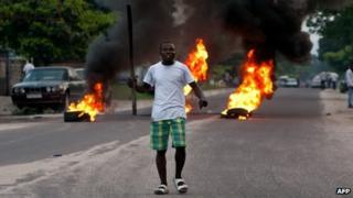 An opposition supporter in front of burning tyres in Kinshasa on 9 December 2011