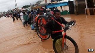 People cross a flooded road in the Sabotsy Namehana commune, north of Antananarivo on 14 February 2012 after Cyclone Giovanna hit Madagascar
