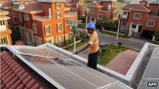 Worker installing solar panels on roof of house