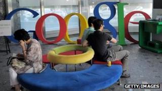 People sit on a sofa in front of a Google logo