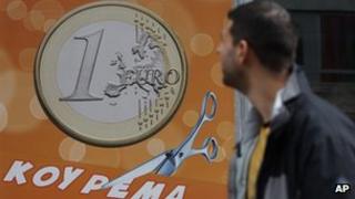 A pedestrian looks at a sign in a shop in Athens reading "One euro, price haircut"