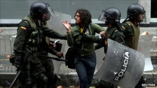 A protester is detained by riot police in Bogota