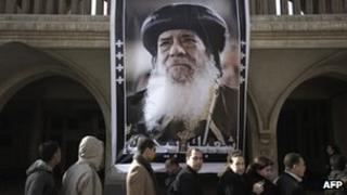 Egyptian Christian Copts wait in a queue next to a poster of Pope Shenouda III at Saint Mark's Coptic Cathedral in Cairo's al-Abbassiya district