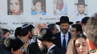 Photos of victims look down from a wall of the Ozar Hatorah Jewish school in Toulouse as mourners gather, 25 March