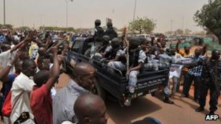 Malian military junta supporters surround a car loaded with soldiers at Bamako airport.