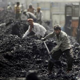 Man shovelling coal at a depot in Jammu, India