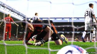 ball in net as goalie looks down at it. Skrtel stands with arms outstretched in background