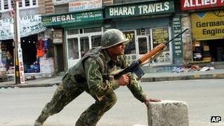 An Indian paramilitary soldier takes cover during a gun battle with militants in Srinagar, India.