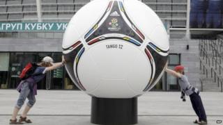 Kids try and push a model of an official Euro 2012 ball