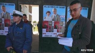 A supporter of the Socialist Forces Front (FFS) party (R) hands out leaflets before their parliamentary election campaign rally in Tizi Ouzou, Algeria