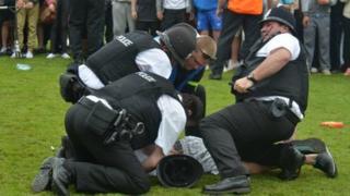 Police arrest a teenager at the match