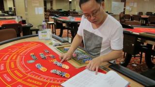 Ng Hoi Wing calculates chip payouts on hands of Baccarat