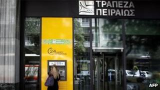 A woman withdraws money from a branch of Piraeus bank in central Athens on May 17
