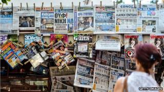 A woman reads newspapers' headlines in Athens