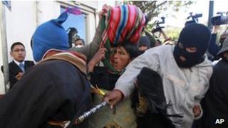 A masked protestor hits an Aymara man trying to enter the plaza in front of the presidential palace