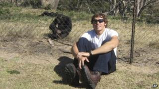 An undated photograph of Andrew Oberle sitting near a chimpanzee.